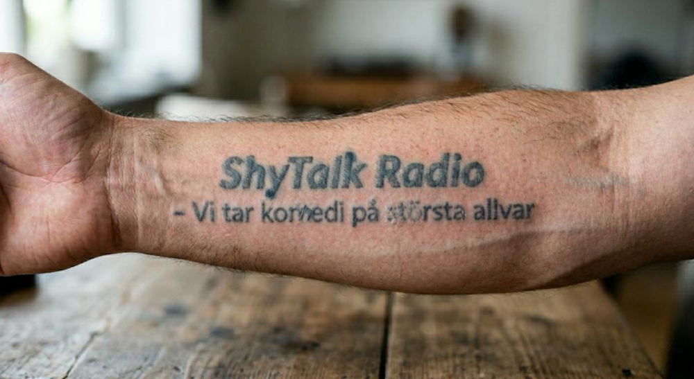 Forearm tattoo reading, "ShyTalk Radio - Vi tar comedy pa stores allvar"