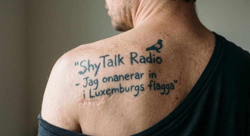 Tattoo reading, "ShyTalk Radio - Jag onanerar in i Luxemburgs flag".